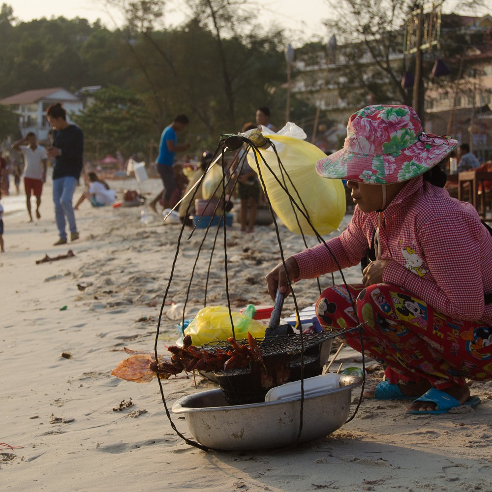 Woman selling grilled squid in Sihanoukville beach, Cambodia